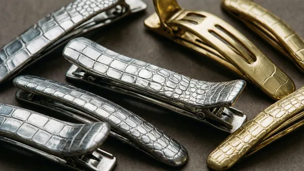 Presilhas jacaré metálicas em tons prateado e dourado sobre bancada de ateliê de laços para bebê